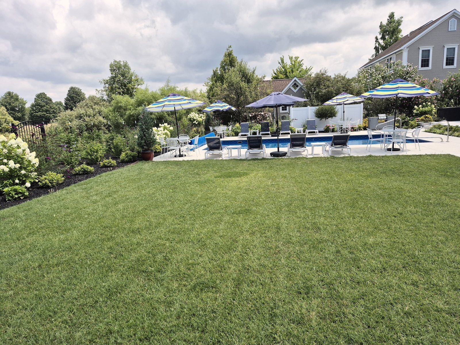 Manicured lawn leading to resort pool deck and patio seating